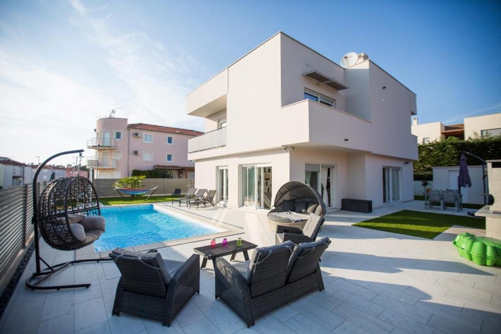 Un patio con piscina y sillas y una casa. en Villa Virtus, en Karigador