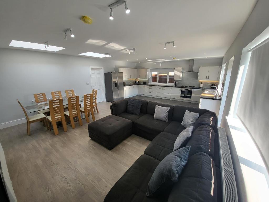 a living room with a couch and a table and a kitchen at High Spec Large 6 Bedroom House! in Kingston upon Thames