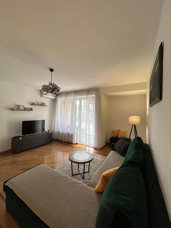 een woonkamer met een groene bank en een tafel bij Vert Apartment in Banja Luka