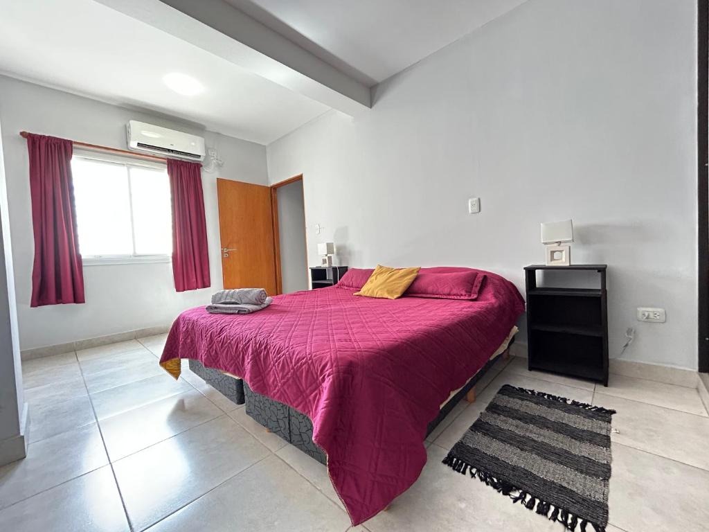 1 dormitorio con 1 cama grande con manta morada en San Antonio departamentos temporarios en Santiago del Estero