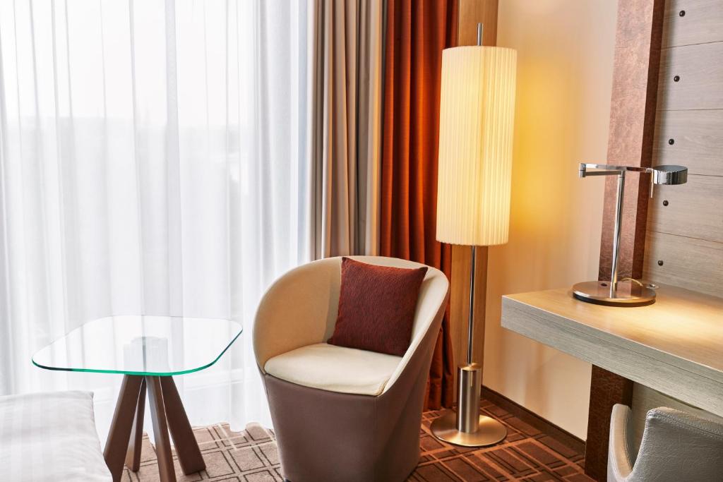 a room with a chair and a table and a lamp at Steigenberger Hotel Bremen in Bremen