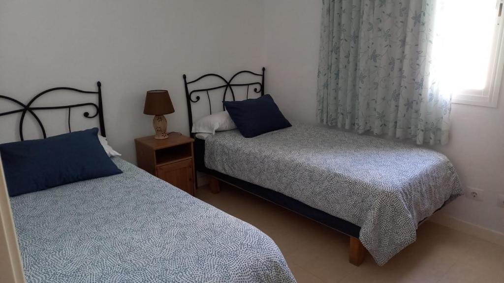 a bedroom with two beds with blue pillows and a window at Casa Lola in Agaete