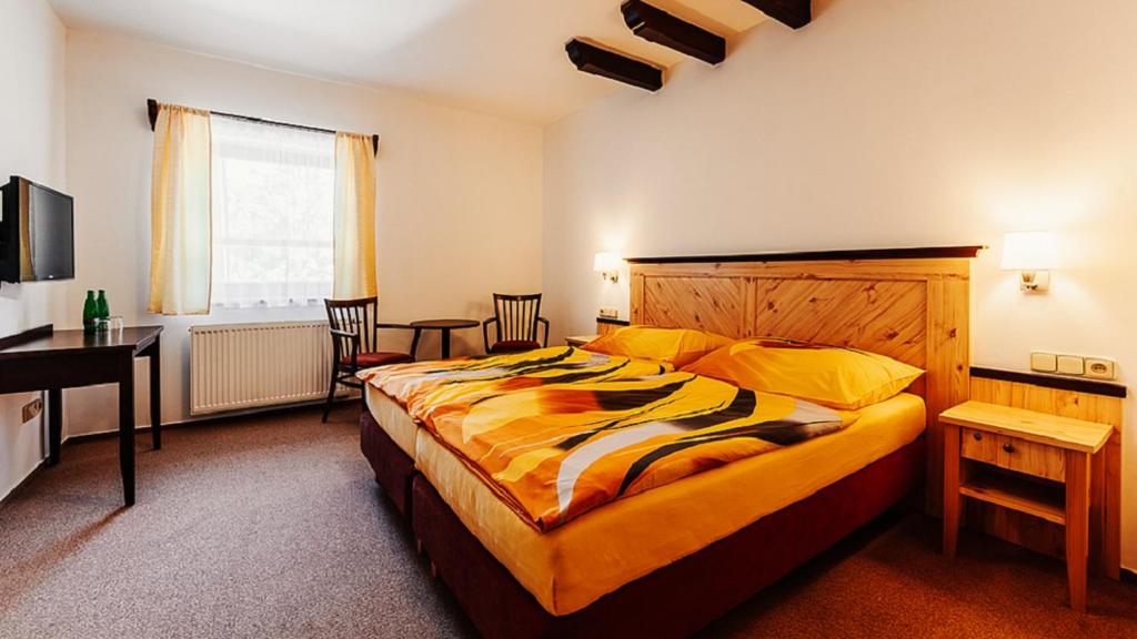 a bedroom with a large bed with a desk and chairs at Hotel Obří Sud Javorník in Jeřmanice