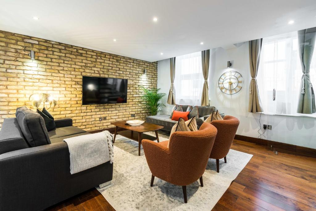 ein Wohnzimmer mit einem Sofa und Stühlen in der Unterkunft Knightsbridge Harrods 2 Bedrooms, 3 Beds, 2.5 Bath in London