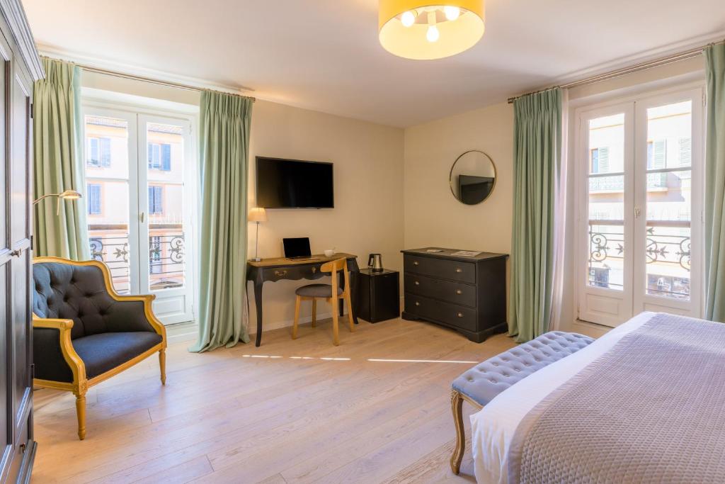 a bedroom with a bed and a chair and a desk at Hotel les Armoiries in Valbonne