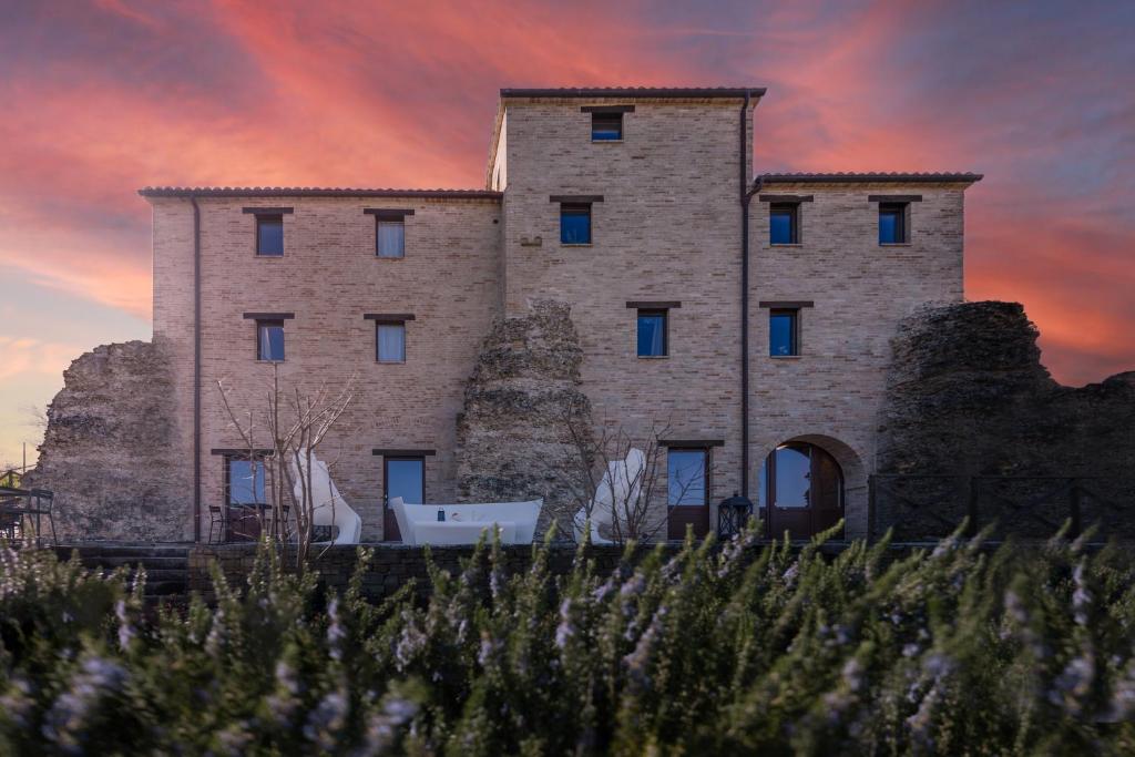 a large stone building with a sunset in the background at DOLF - Porta Gemina in Urbisaglia