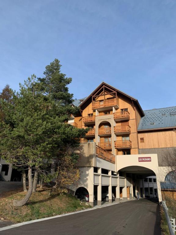 duży drewniany budynek z drzewem przed nim w obiekcie STUDIO Aux 2 ALPES w mieście Vénosc
