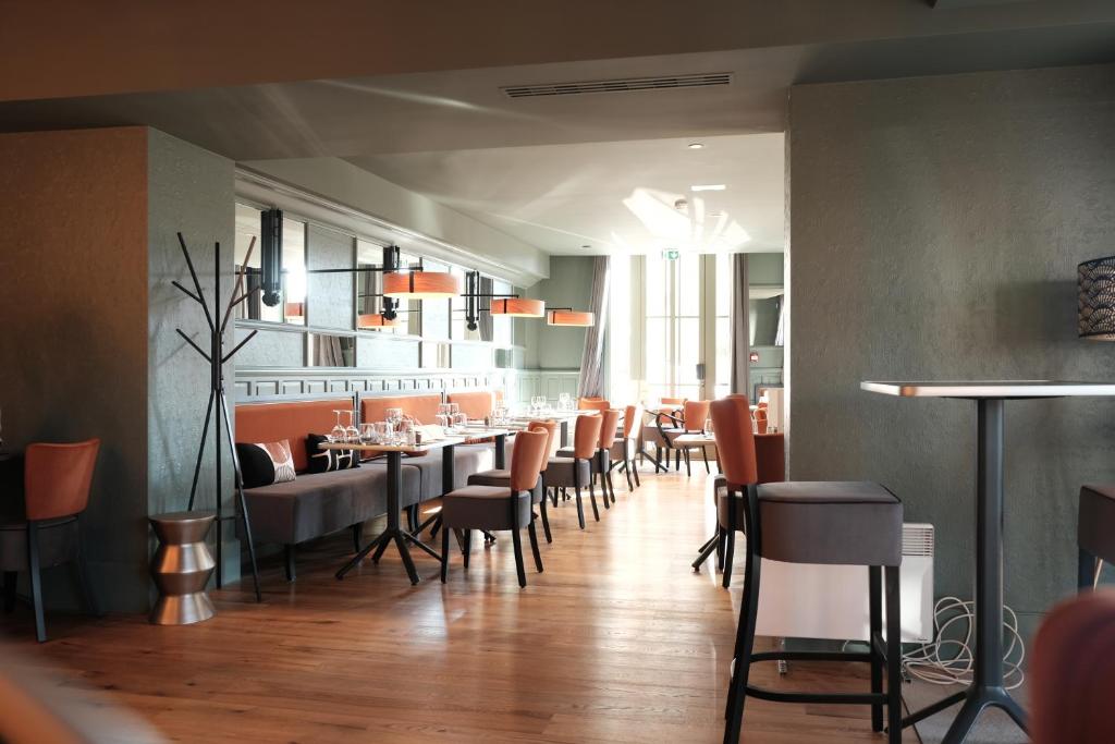 een restaurant met stoelen en tafels in een kamer bij Mage hôtels - Hôtel la grenette in Roanne