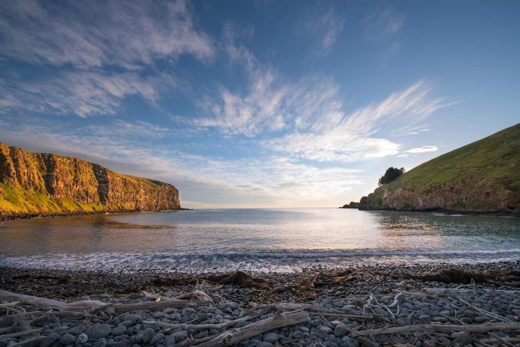 a beach with a rocky shoreline and the ocean at Annandale Coastal Farm Escape & Luxury Villa Collection in Akaroa