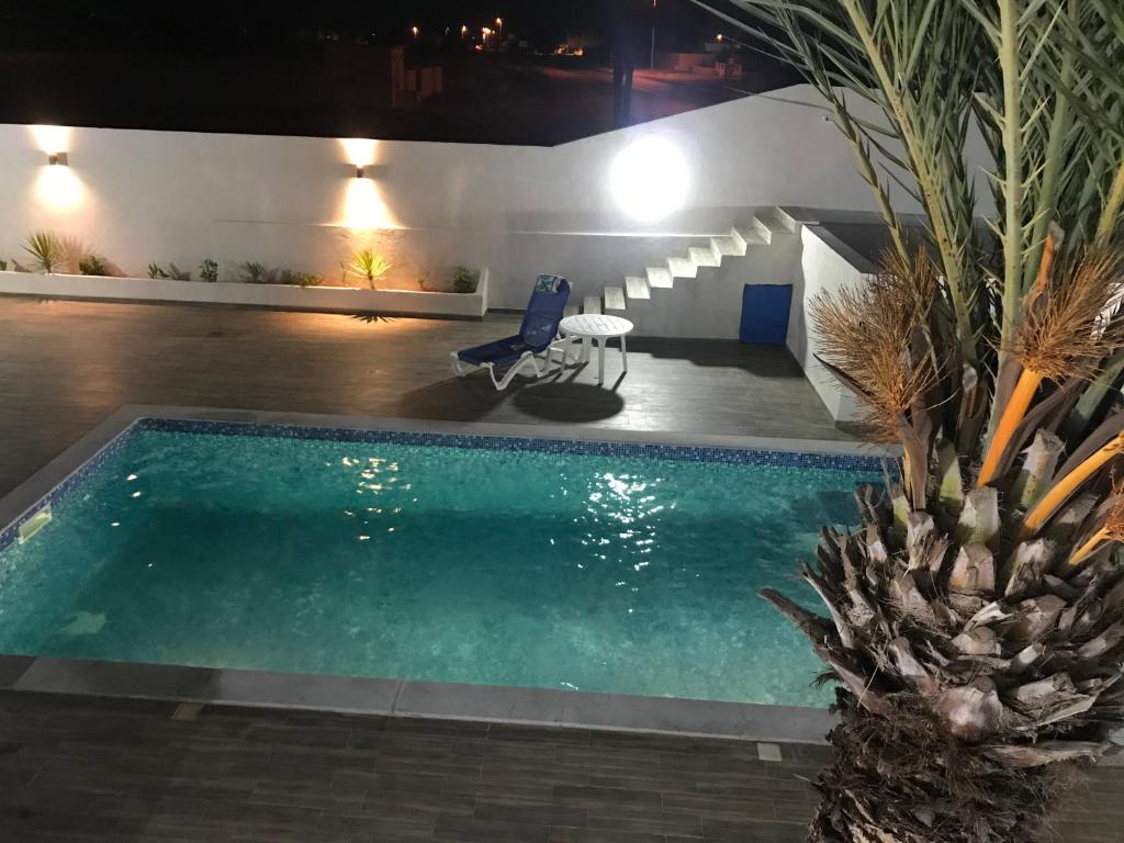a swimming pool at night with a palm tree next to it at Dar Slima in Aghīr