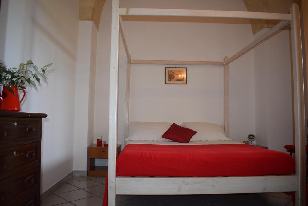 um quarto com uma cama com uma colcha vermelha em La Cecia - Casa vacanze nella campagna salentina em Cavallino di Lecce