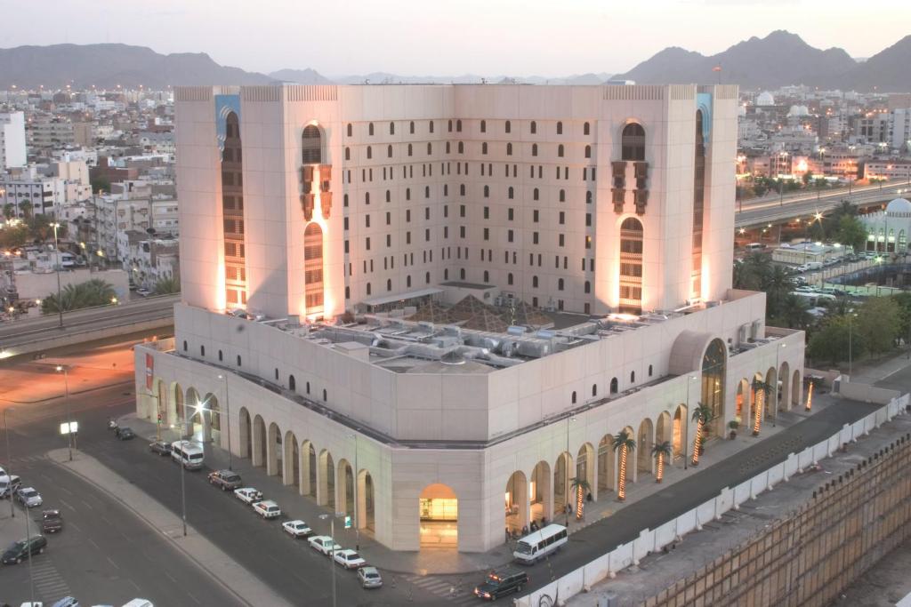 a large white building with cars parked in front of it at New Madinah Hotel in Medina