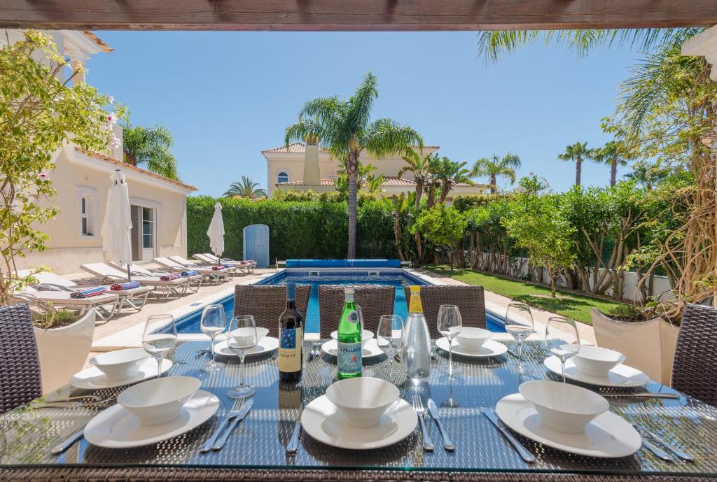 Endless Summer Luxury Villa في كينتا دو لاغو: طاولة مع كؤوس وزجاجات النبيذ على الفناء