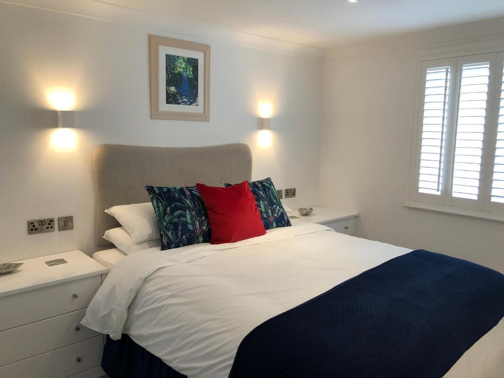 a bedroom with a white bed with a red pillow at Stylish Sea View Apartment with Parking in Penzance