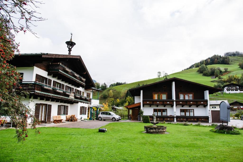 a house with a green hill in the background at Appartements Dreimäderlhaus in Maria Alm am Steinernen Meer