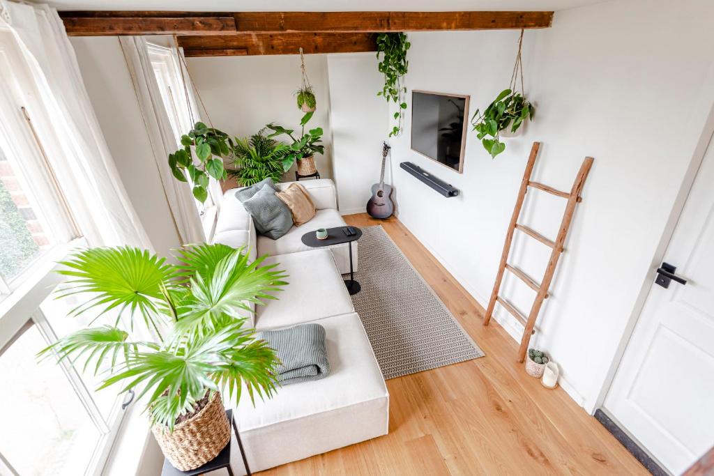un soggiorno con mobili bianchi e piante di Railway Forge Loft a Haarlem
