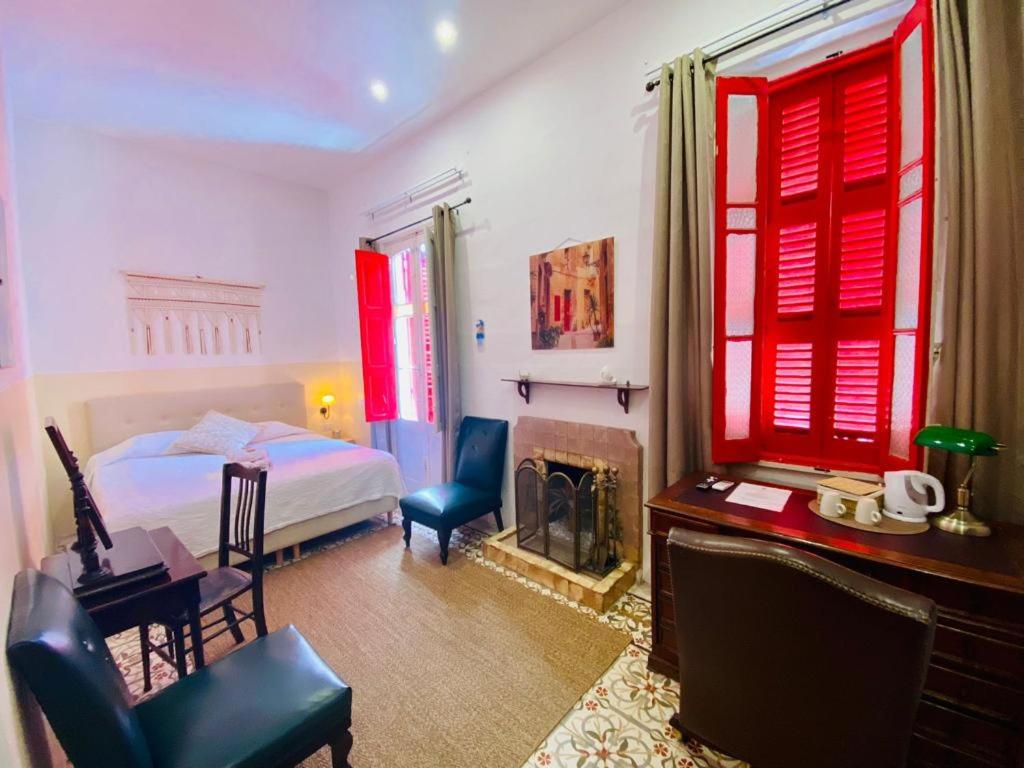 a bedroom with red windows and a bed and a desk at The Maltese Sun in Sliema