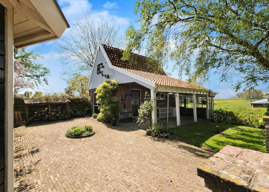 una pequeña casa blanca con entrada de ladrillo en Idyllisch en knus huisje met prachtige veranda. en Oterleek