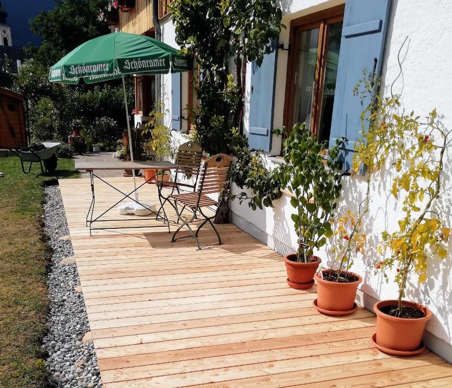 una terraza de madera con mesa, sillas y sombrilla en Lieblingsort, en Unterwossen
