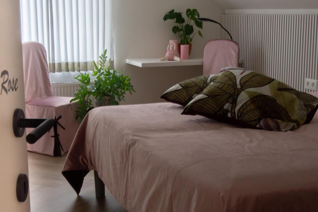 ein Schlafzimmer mit einem Bett und einem rosa Stuhl in der Unterkunft B&B Bergdal in Gits