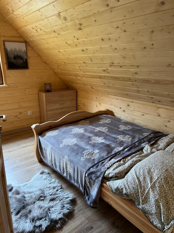 a bedroom with a bed in a wooden room at Leśny Domek in Brenna