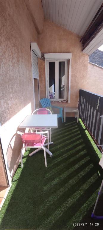 ナルボンヌにあるAppartement avec Terrasseのパティオ(芝生の上にテーブルと椅子付)