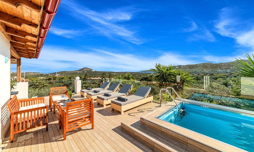 a deck with a swimming pool and chairs next to a house at Villa Carolina Private Pool in Agios Nikolaos