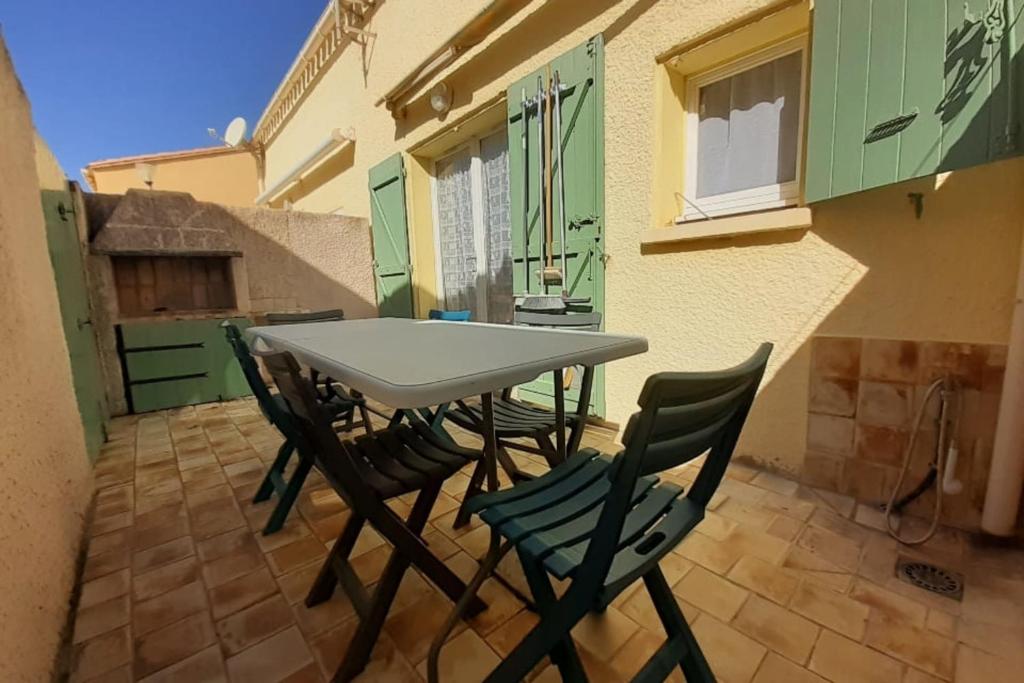 uma mesa e cadeiras no pátio de um edifício em Small villa 40m with terrace near the beach em Fleury