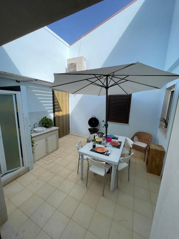 a dining room with a table and an umbrella at Genova La casa di Saretta in Marina di Ragusa