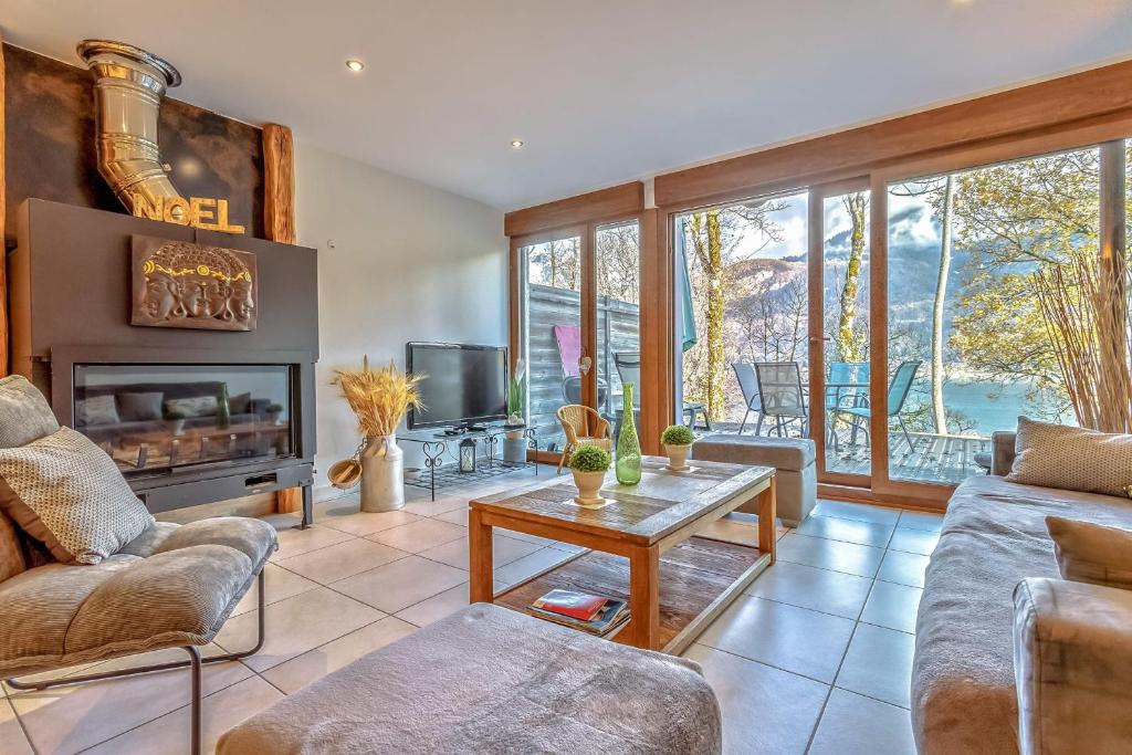 ein Wohnzimmer mit einem Sofa und einem Tisch in der Unterkunft Les Terrasses de Bredanne in Doussard