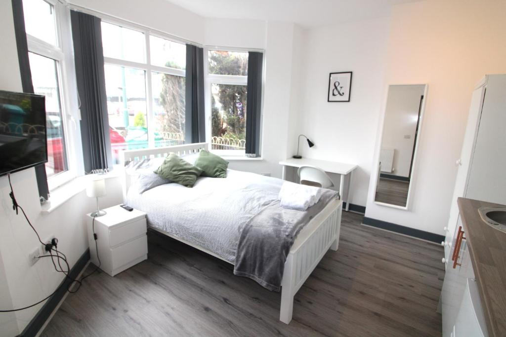 a white bedroom with a bed and windows at Newly refurbished studio, great location 8 studios in Nottingham