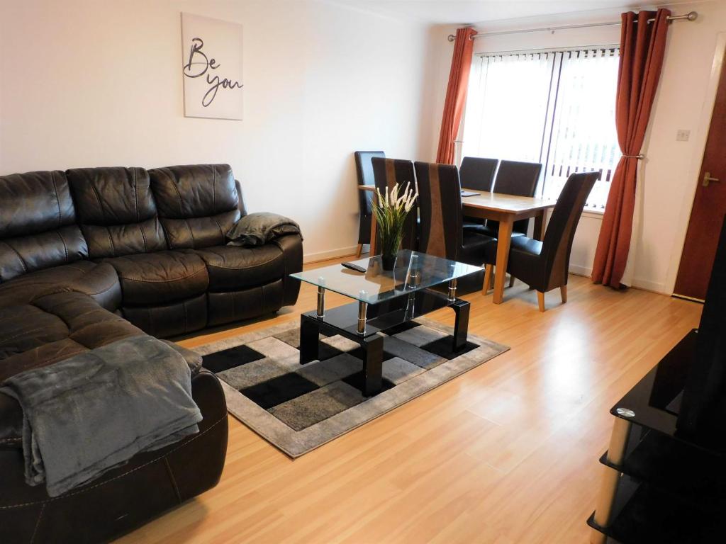 ein Wohnzimmer mit einem Ledersofa und einem Tisch in der Unterkunft 2 bed Apt on Quiet Cul-de-Sac, Fab Location in Paisley