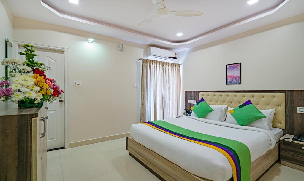 a bedroom with a large bed and a vase of flowers at Treebo Trend Elite 7 in Bangalore
