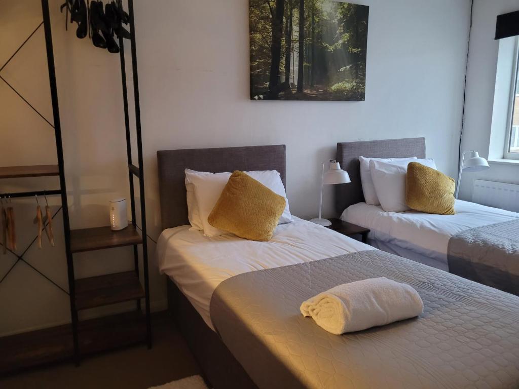 um quarto com duas camas com almofadas amarelas em Rent Unique the Otford modern home 1 bed with mezzanine em Crawley