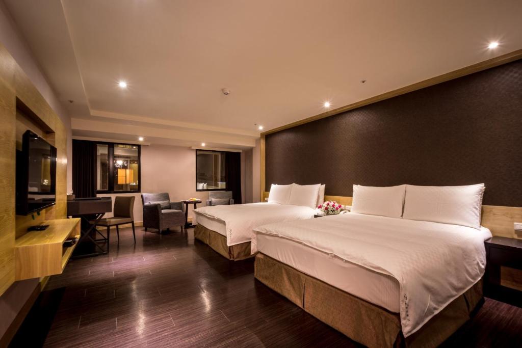 a hotel room with two beds and a table and chairs at Chateau-Rich Hotel in Tainan