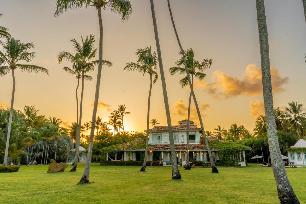 a house surrounded by palm trees at sunset at Casa Brasileira - Hotel Galeria in Pôrto de Pedras