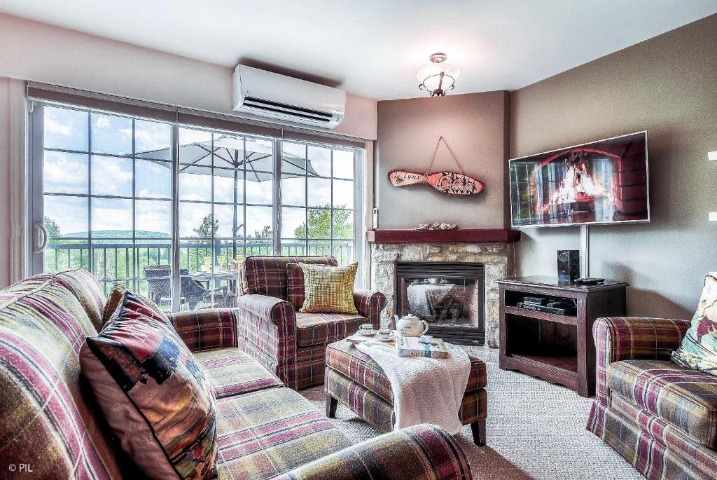 a living room with two couches and a fireplace at Mont-blanc Ski Inout Condo W Pool Beach Access in Saint-Faustin