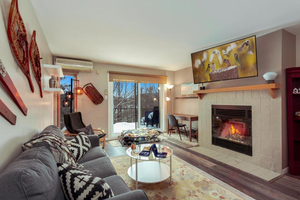 a living room with a couch and a fireplace at Tremblant Rocher Soleil Ski In Ski Out 2 Bedroom in Mont-Tremblant