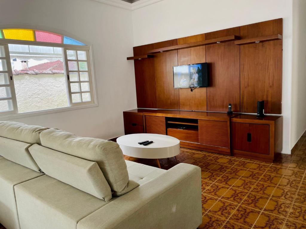 uma sala de estar com um sofá e uma televisão em Hostel Litoral em Peruíbe