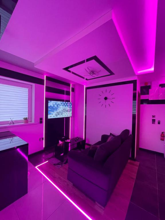 #5 TGHA Luxury One Bedroom Apartment in Athlone في آثلون: غرفة معيشة مع إضاءة وردية وأريكة