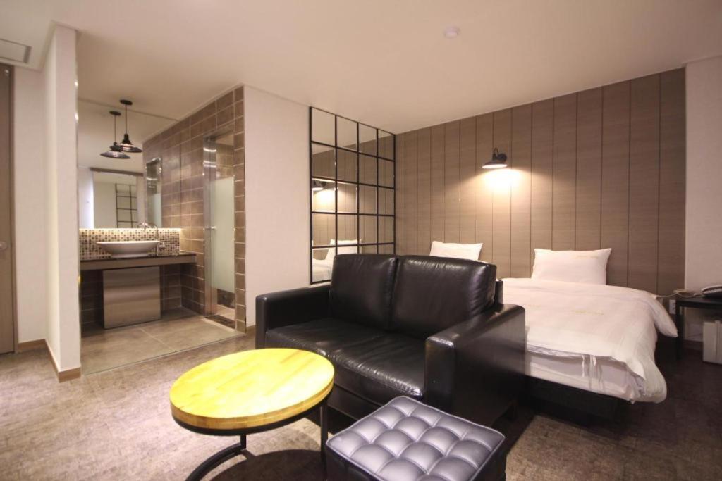 um quarto com uma cama, um sofá e uma mesa em Paradise Hotel em Gunsan