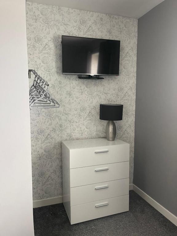 a television on a wall with a dresser with a lamp at Kevara Self-Catering in Finstown