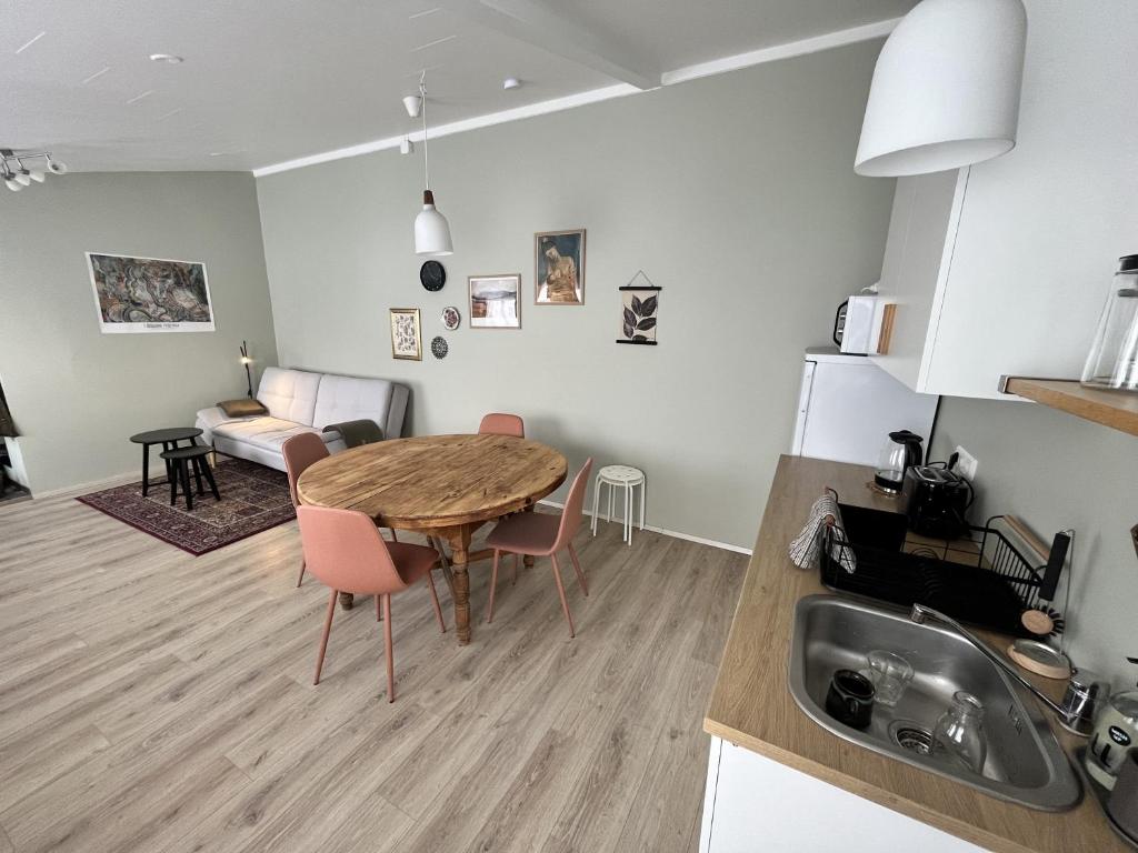 a kitchen and living room with a wooden table and a dining room at Bridge Apartment in Egilsstadir