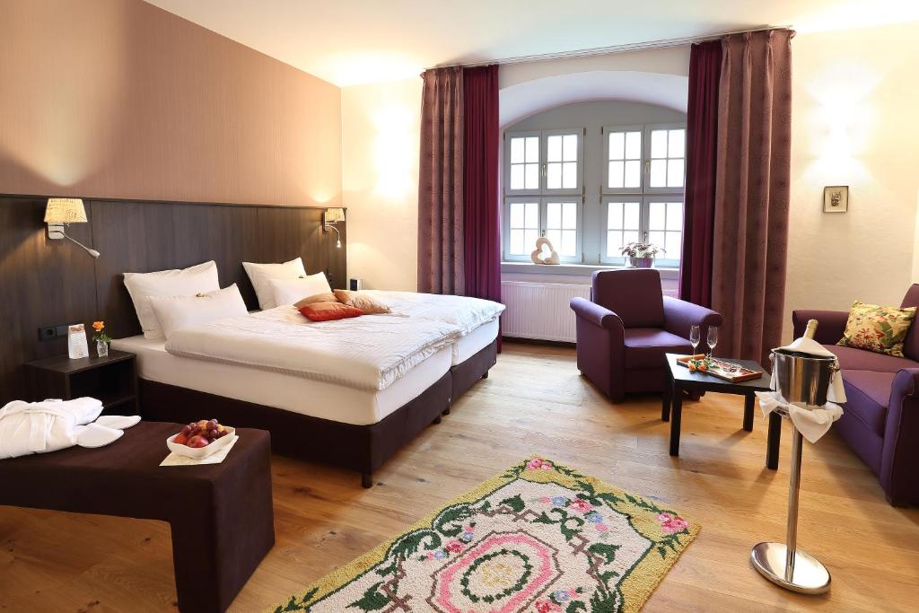 um quarto de hotel com uma cama e um sofá em Hotel Garni Schloß Schönberg em Bad Brambach