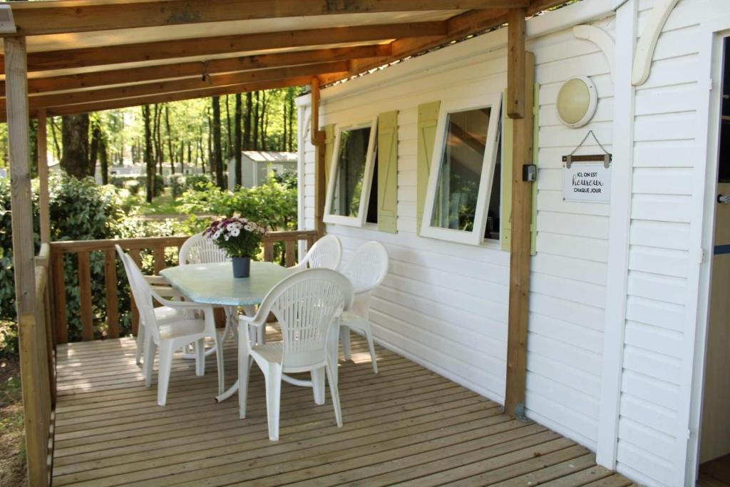 um deque de madeira com uma mesa e cadeiras em MOBILHOME PROCHE DU PUY DU FOU em La Boissière-de-Montaigu