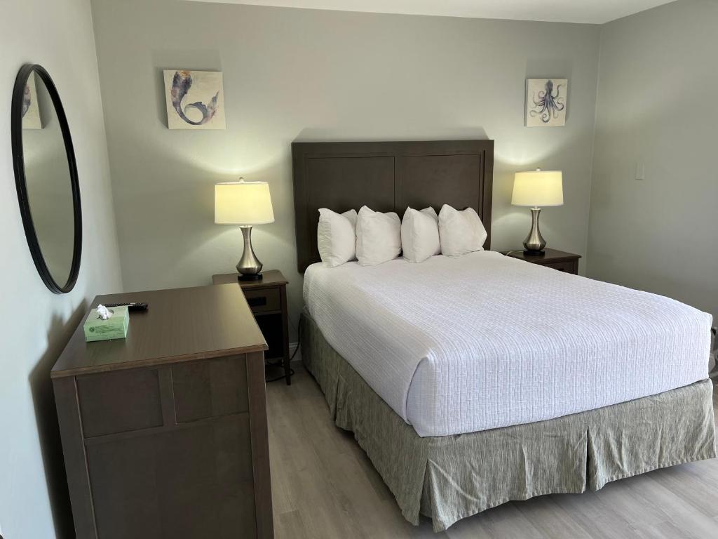 a bedroom with a bed with two lamps and a mirror at Marco Island Lakeside Inn in Marco Island