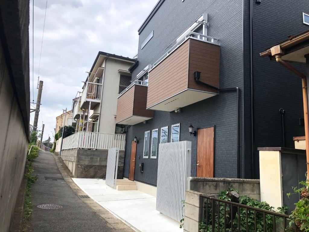 a black house with a wooden door on a street at Maisonette Hanazono - Vacation STAY 63319v in Kemigawa-machi