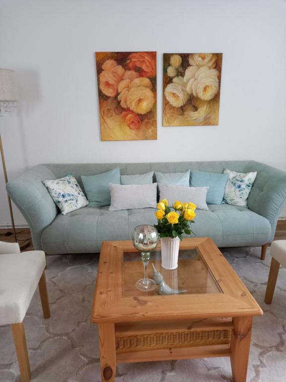 a living room with a couch and a table with flowers at Pine Crest Ferienwohnung in Harzgerode