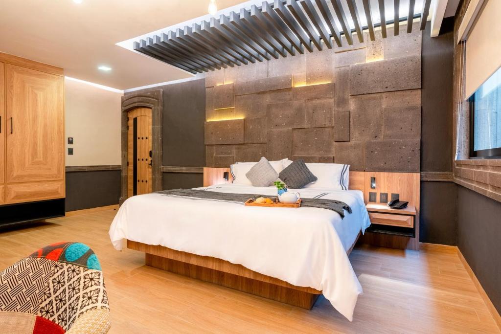 una camera con un grande letto e un muro di Hotel Patio Santiago a Querétaro