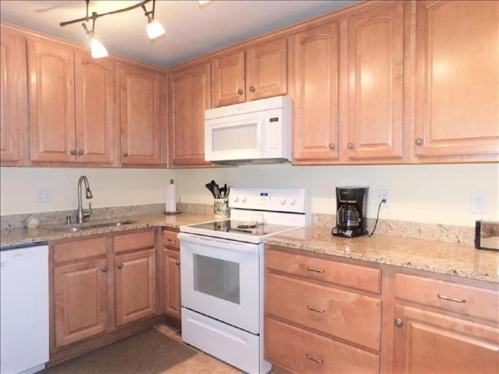 eine Küche mit Holzschränken und weißen Geräten in der Unterkunft S6 family friendly near tennis and pool peaceful upstairs very neat and well equipped family comfort in Mallory Park